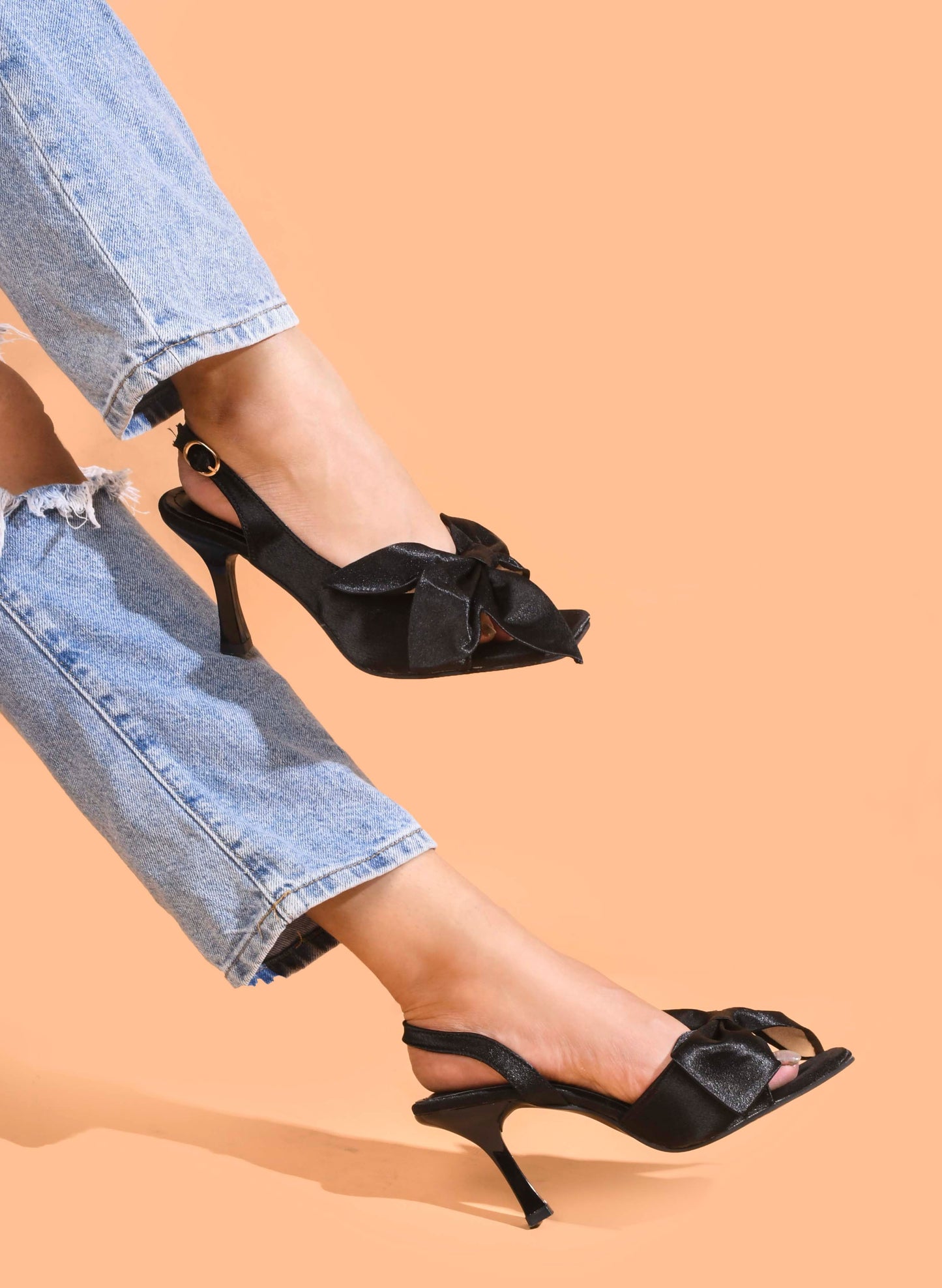 elegant heels featuring a large bow detail on the front and an ankle strap
Black