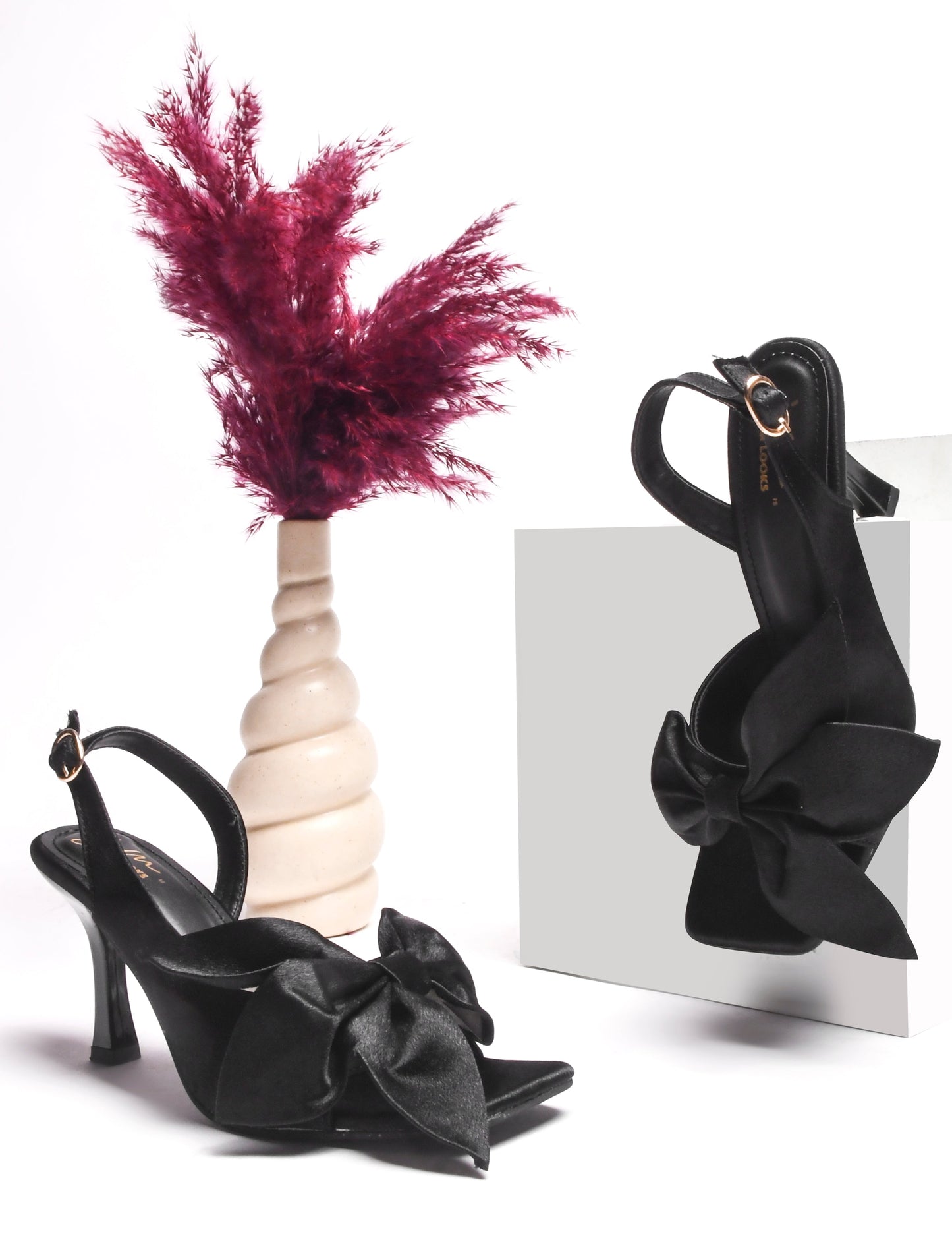 elegant heels featuring a large bow detail on the front and an ankle strap
Black
