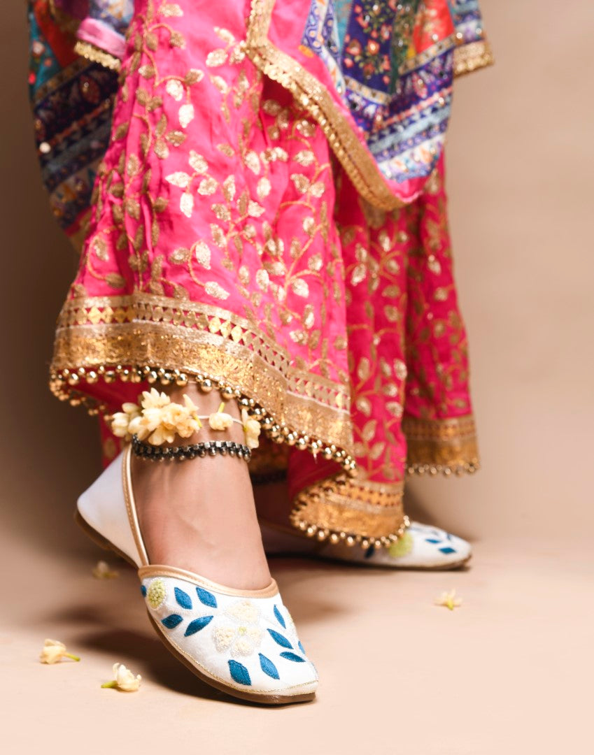 exquisitely embroidered juttis featuring floral and leaf patterns
White