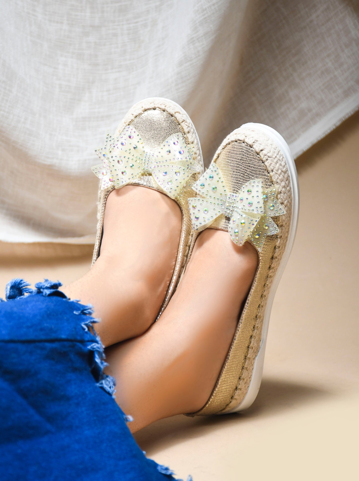 JM Looks espadrille loafers featuring a shimmering toe, a rhinestone-embellished bow, and a woven sole
Golden