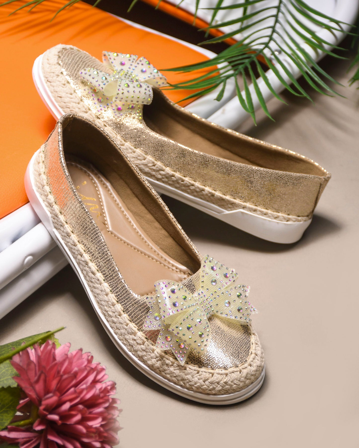 JM Looks espadrille loafers featuring a shimmering toe, a rhinestone-embellished bow, and a woven sole
Golden
