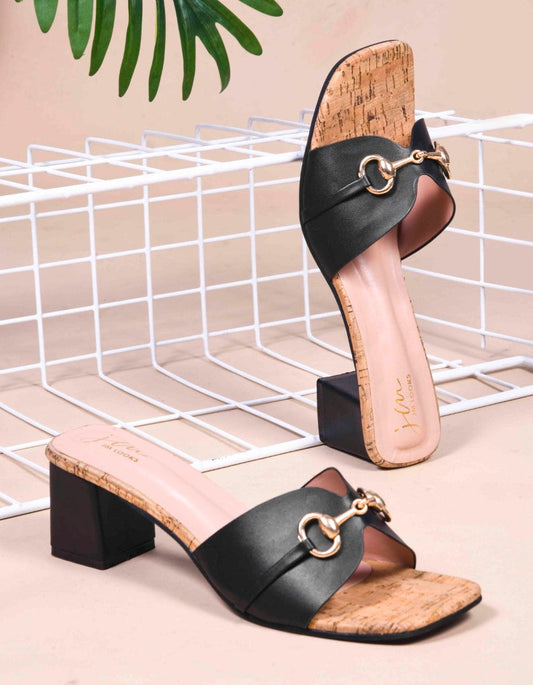 women's mules featuring a wide strap with a buckle embellishment and a cork-textured block heel
 Black