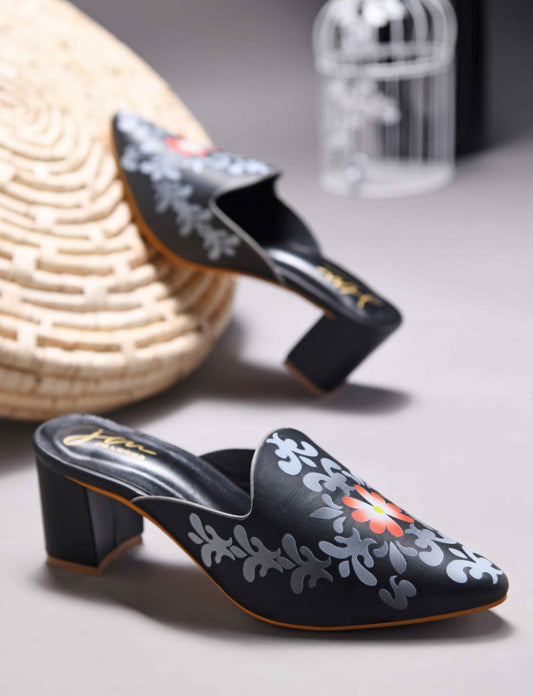 A women's mule shoe featuring a charming floral design and a block heel
 Black