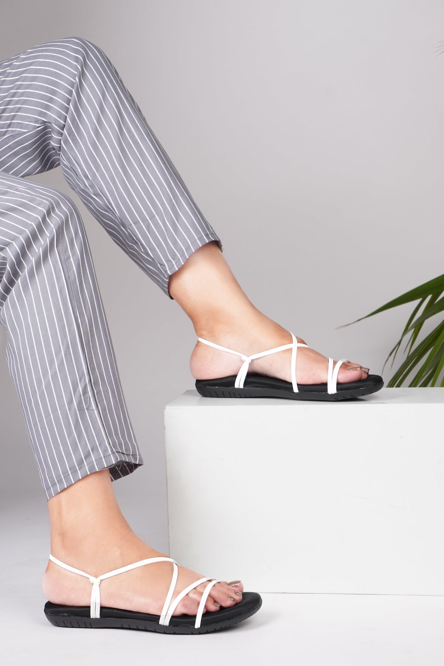 White strappy flat sandals with glossy thin cross straps and slingback ankle strap