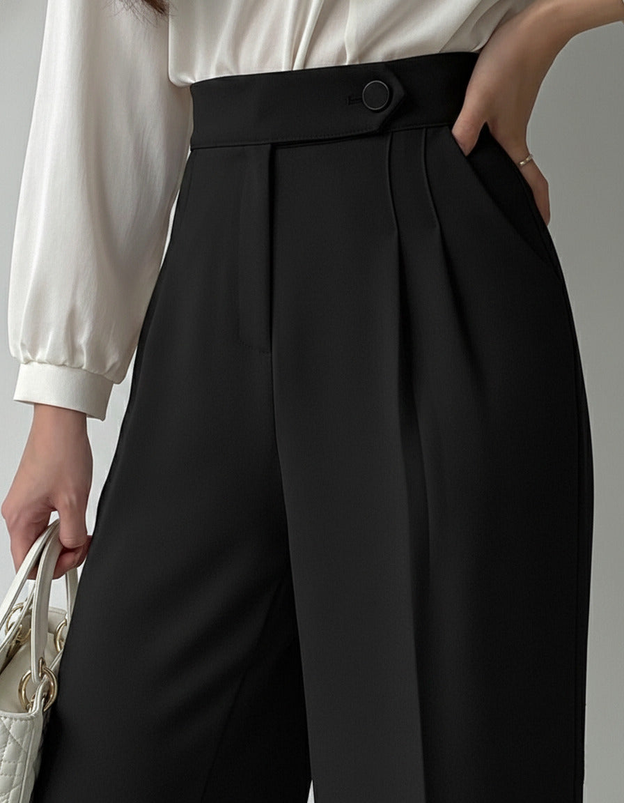 Black high-waisted wide-leg pleated trousers for women styled with white blouse and embellished pointed satin heels