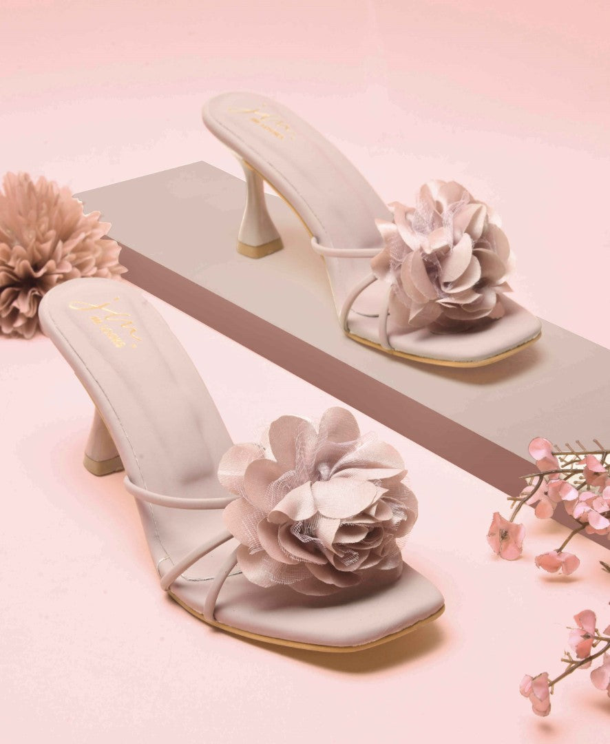 women's heeled mules featuring a large floral embellishment on the strap
Purple