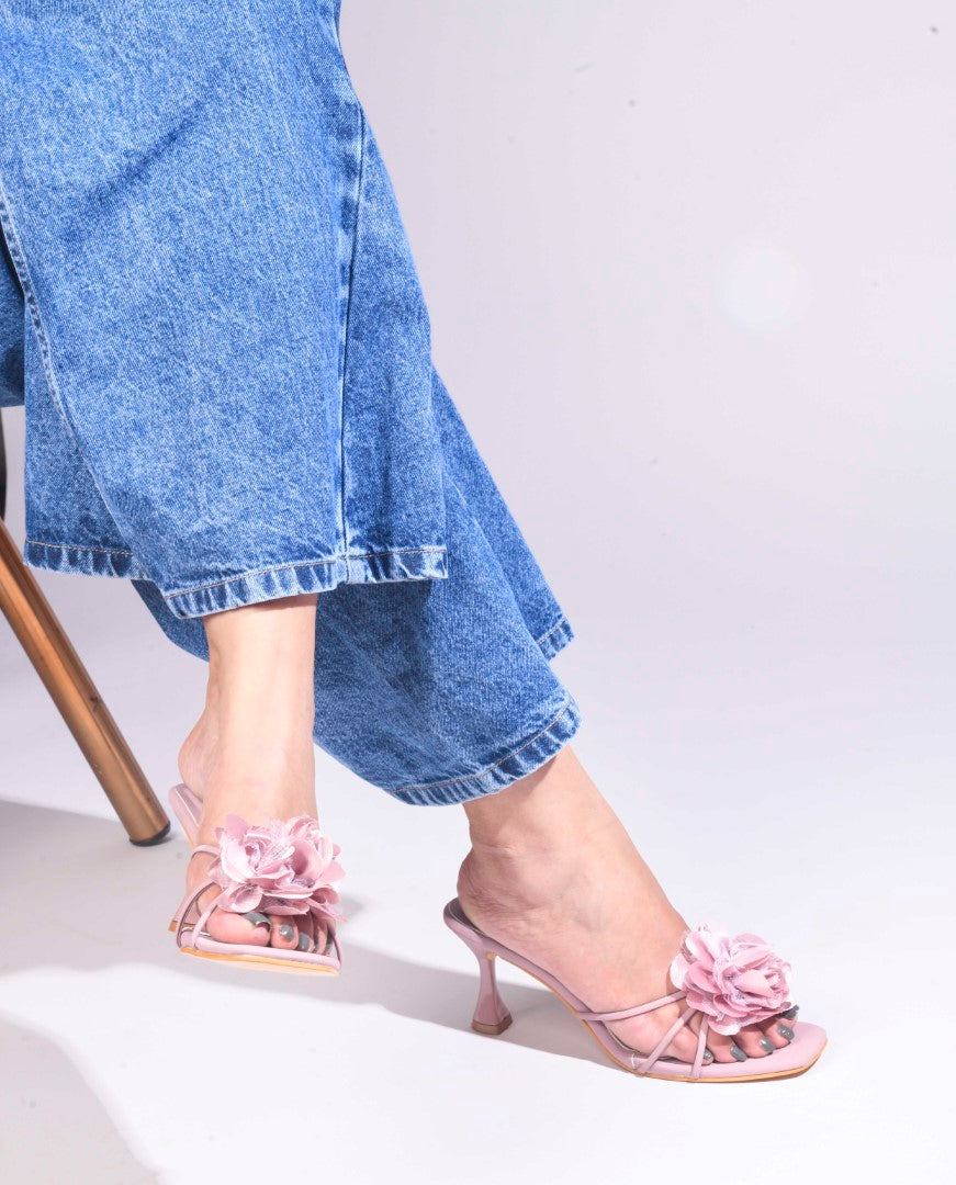women's heeled mules featuring a large floral embellishment on the strap
Nude