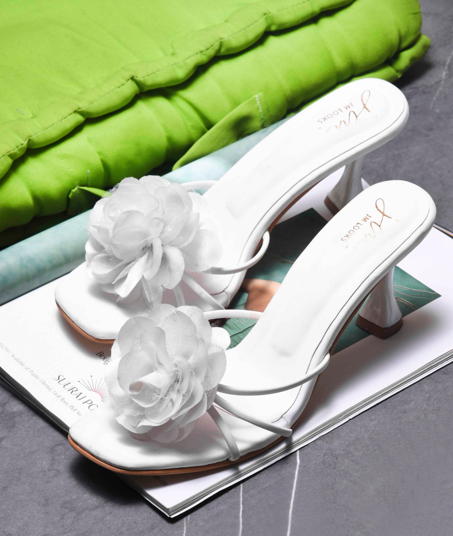 women's heeled mules featuring a large floral embellishment on the strap
White