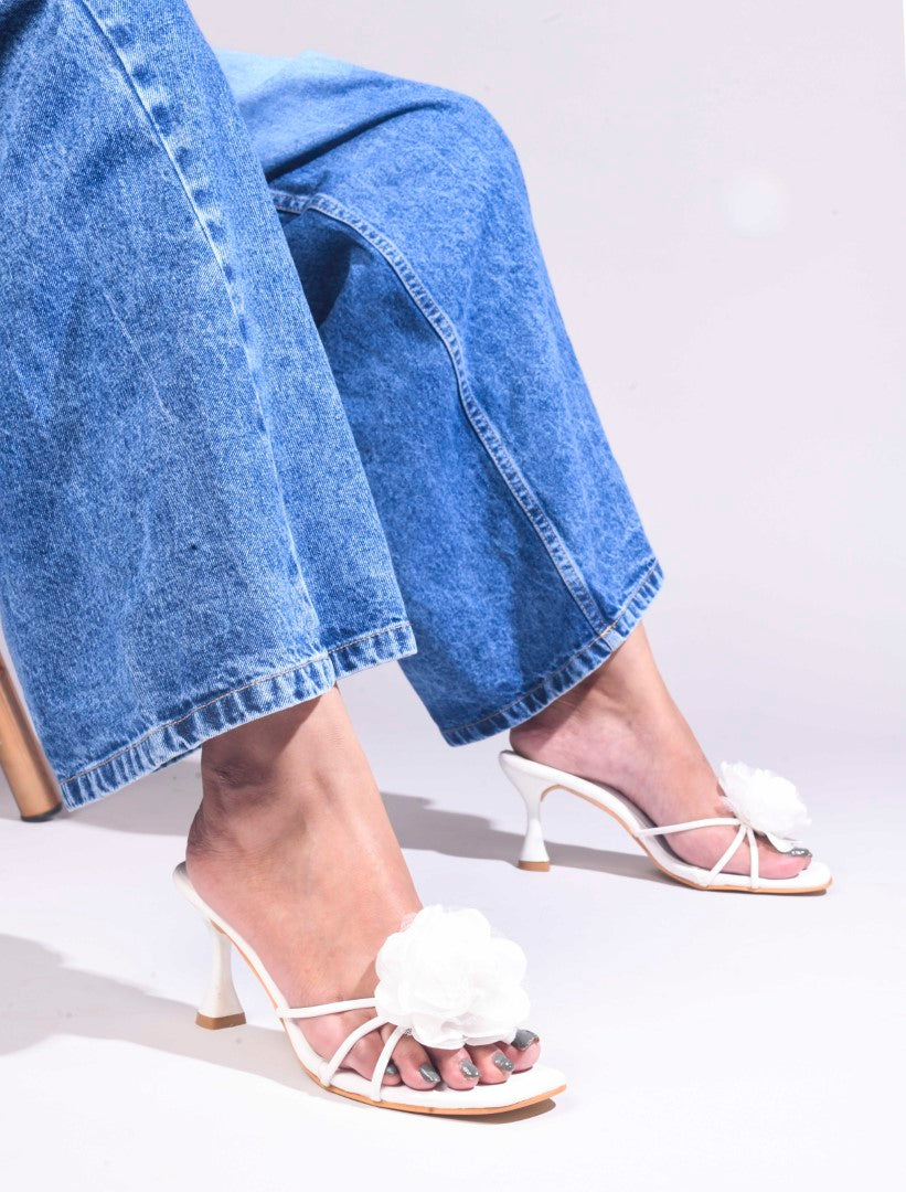 women's heeled mules featuring a large floral embellishment on the strap
White