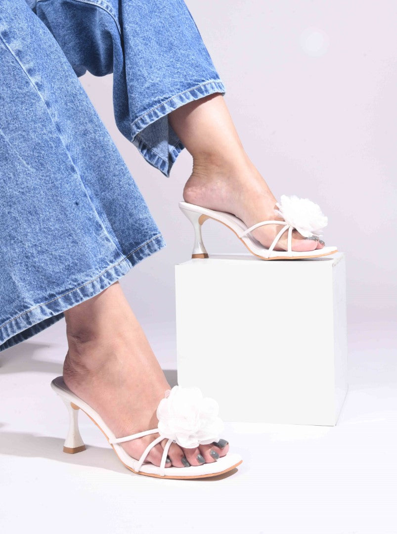 women's heeled mules featuring a large floral embellishment on the strap
White