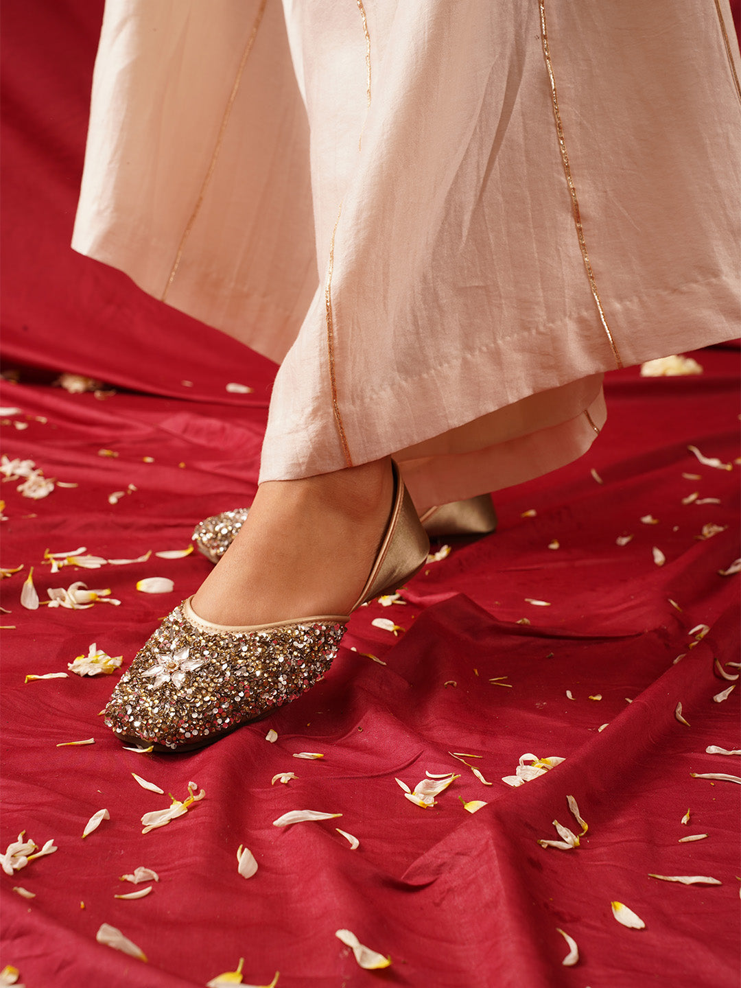 traditional juttis heavily embellished with sequins and a large floral motif at the toe
Green