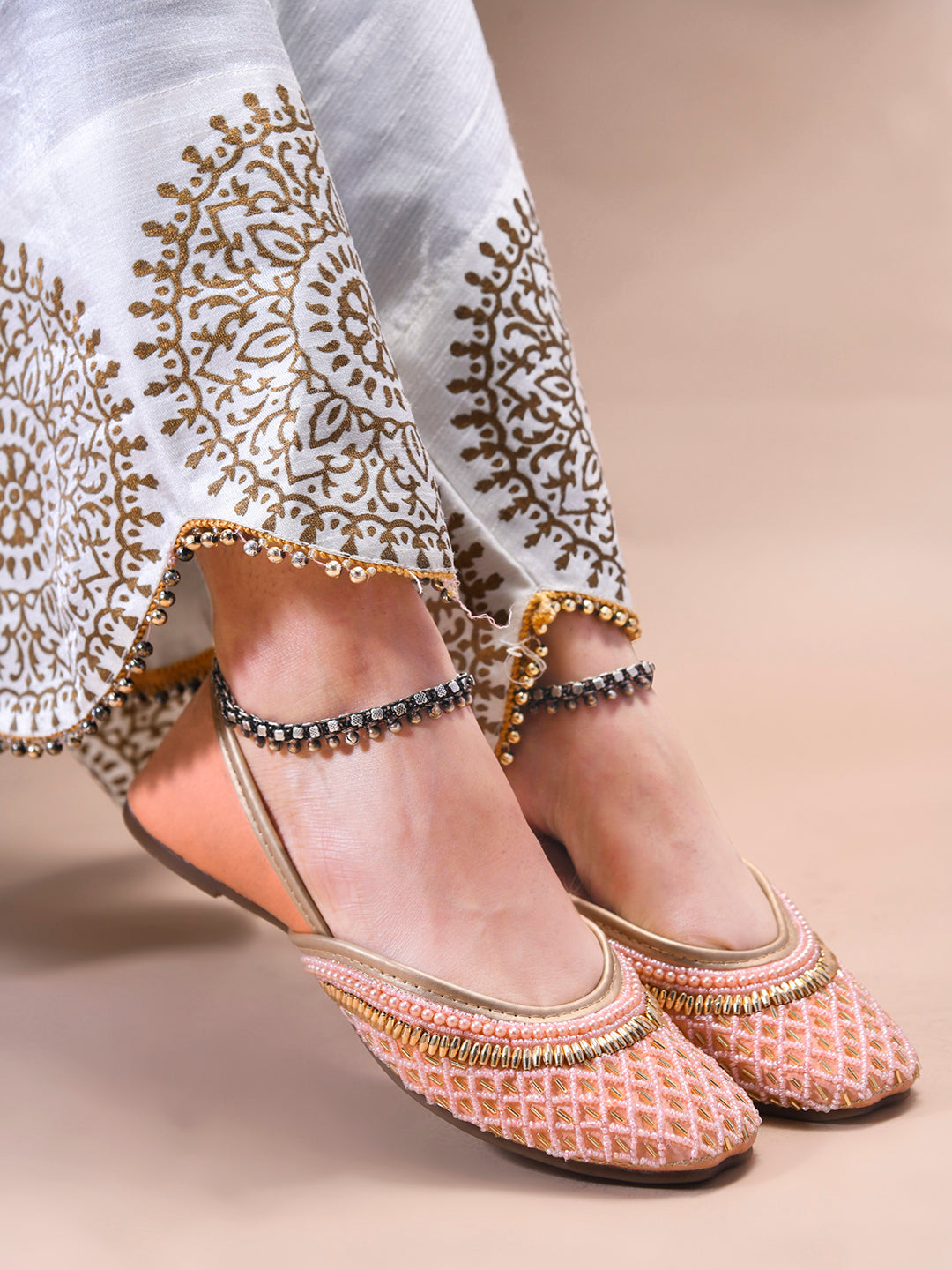 traditional juttis with intricate beaded work in a geometric pattern on the upper
Peach