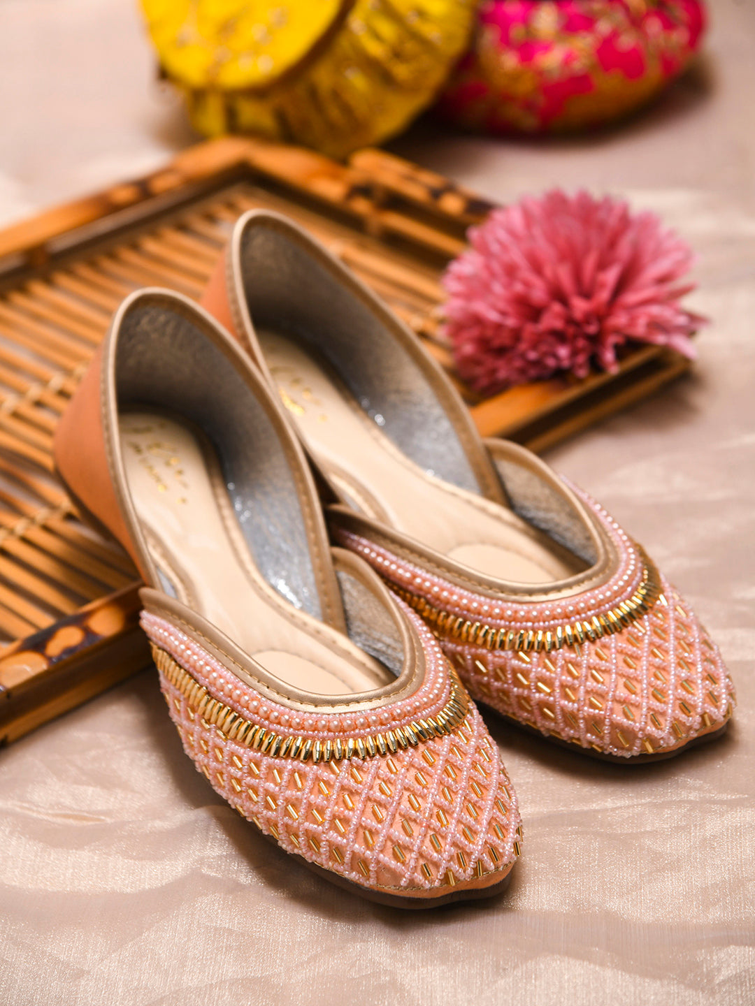 traditional juttis with intricate beaded work in a geometric pattern on the upper
Peach