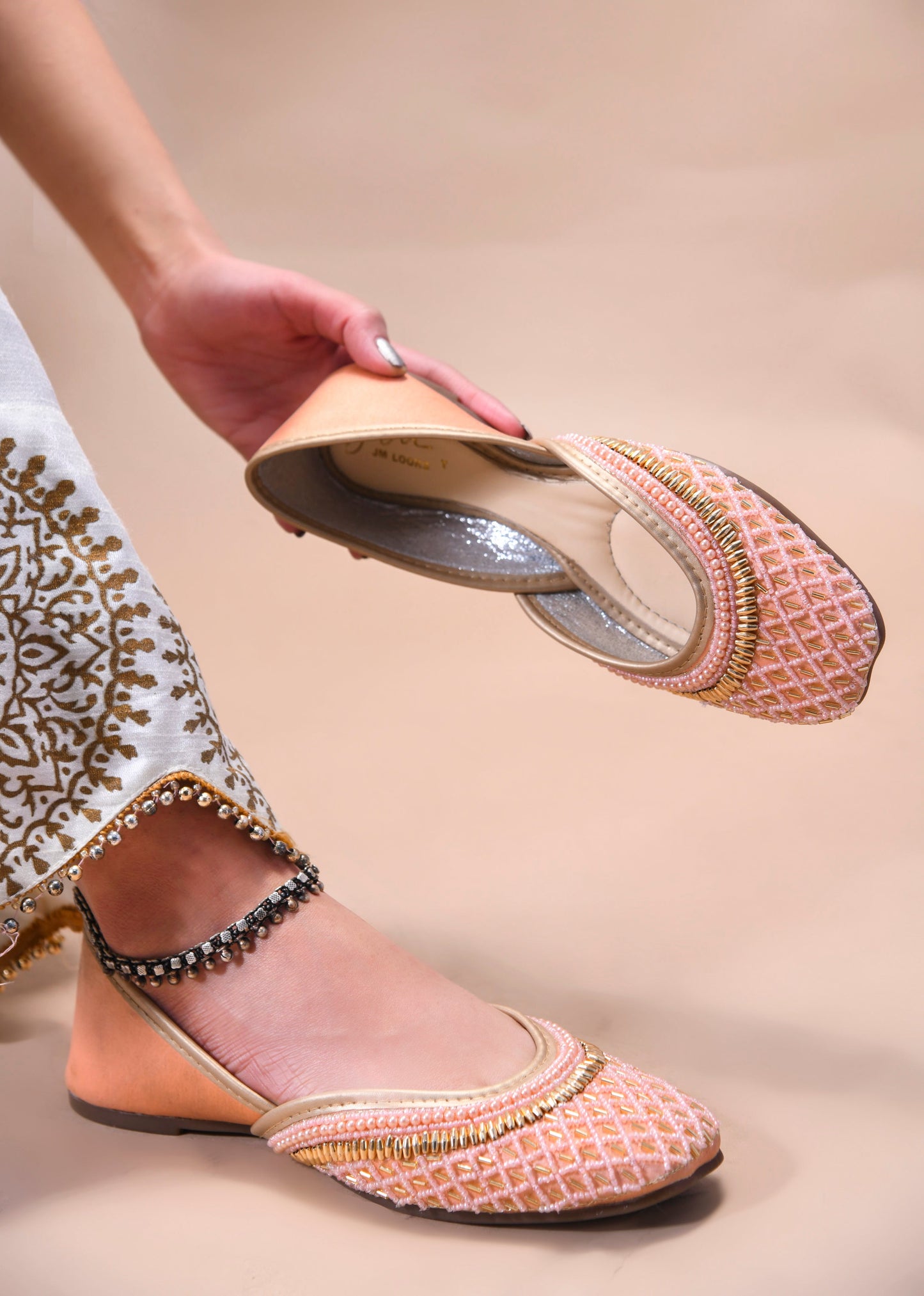 traditional juttis with intricate beaded work in a geometric pattern on the upper
Peach