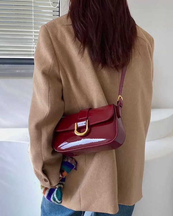 Red crossbody shoulder bag with gold U-shaped buckle, adjustable strap, and glossy leather finish for women
