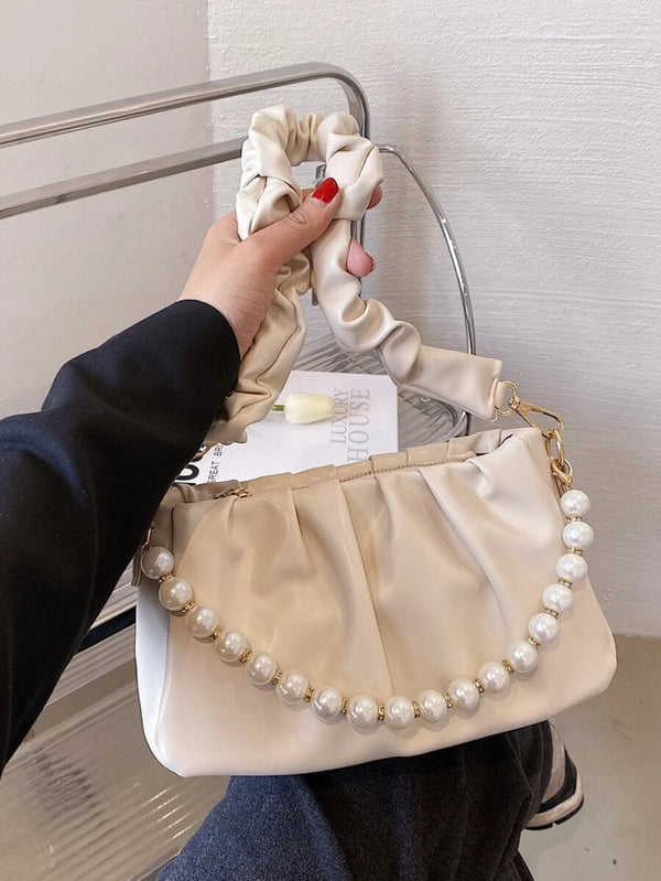 Cream pleated shoulder bag featuring a ruched handle, gold hardware, and pearl chain strap for women.