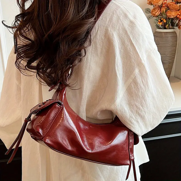 Red glossy hobo shoulder bag with adjustable strap, side lace-up pockets, and sleek zip closure design