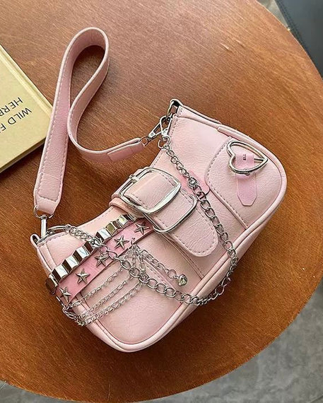 Baguette bag in pink featuring silver studs, star accents, buckle detail, layered chains, and heart charm