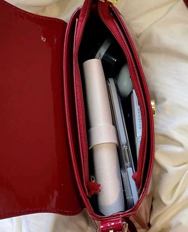 Red crossbody shoulder bag with gold U-shaped buckle, adjustable strap, and glossy leather finish for women