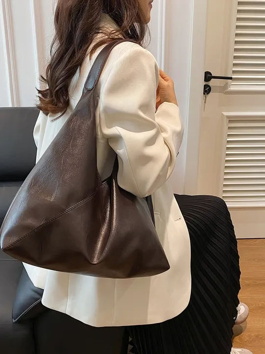 Brown vegan leather hobo tote bag with single shoulder strap, wrinkled texture, asymmetric zigzag silhouette.