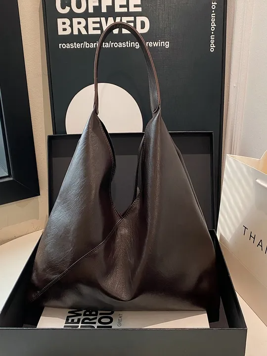 Brown vegan leather hobo tote bag with single shoulder strap, wrinkled texture, asymmetric zigzag silhouette.