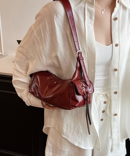 Red glossy hobo shoulder bag with adjustable strap, side lace-up pockets, and sleek zip closure design