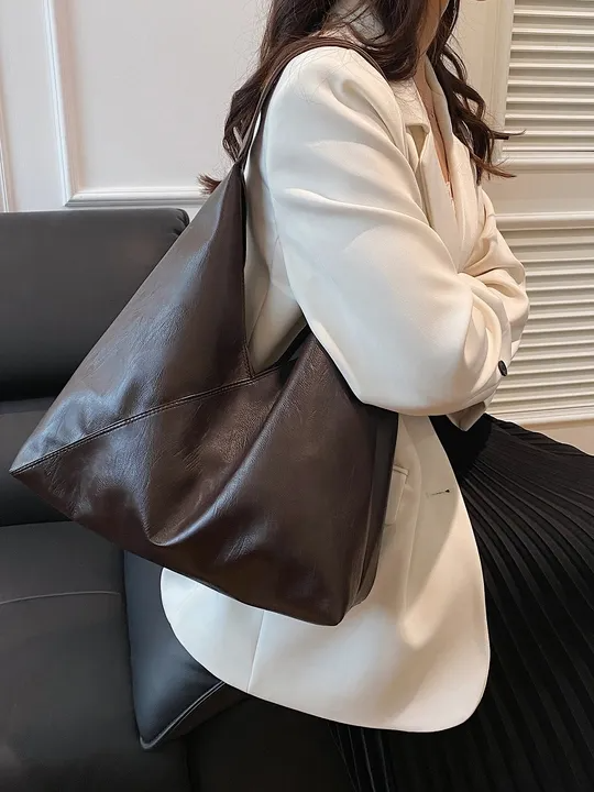 Brown vegan leather hobo tote bag with single shoulder strap, wrinkled texture, asymmetric zigzag silhouette.
