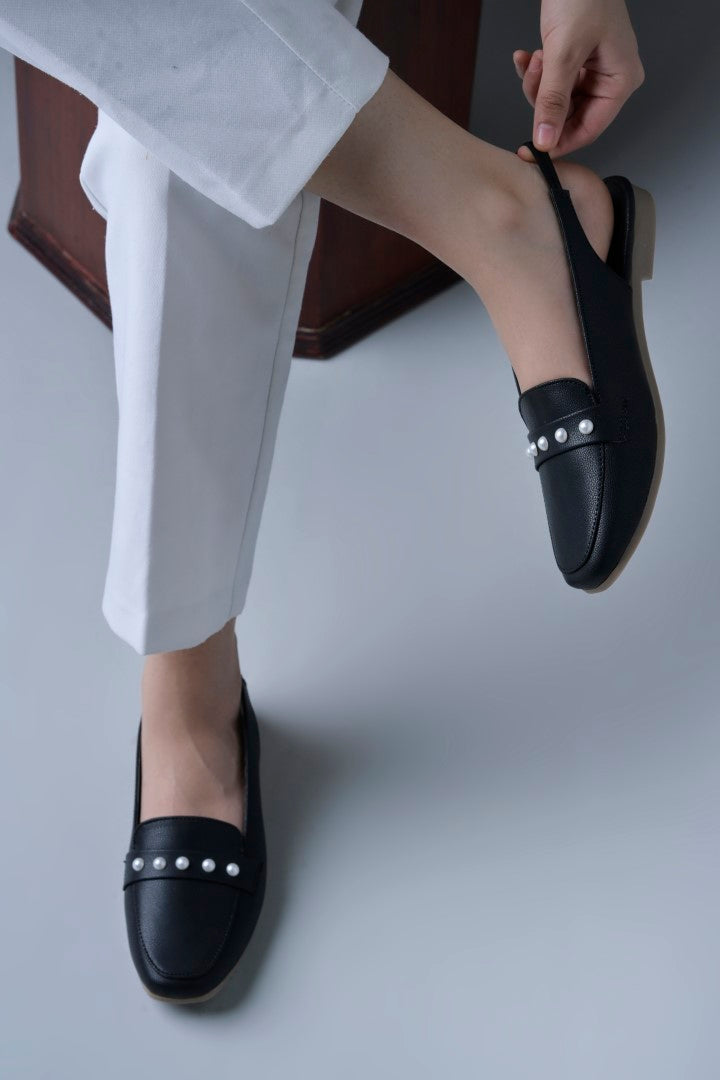 Jm Looks beige slingback loafers adorned with small pearls on the vamp, with a string of pearls in the background
 Black