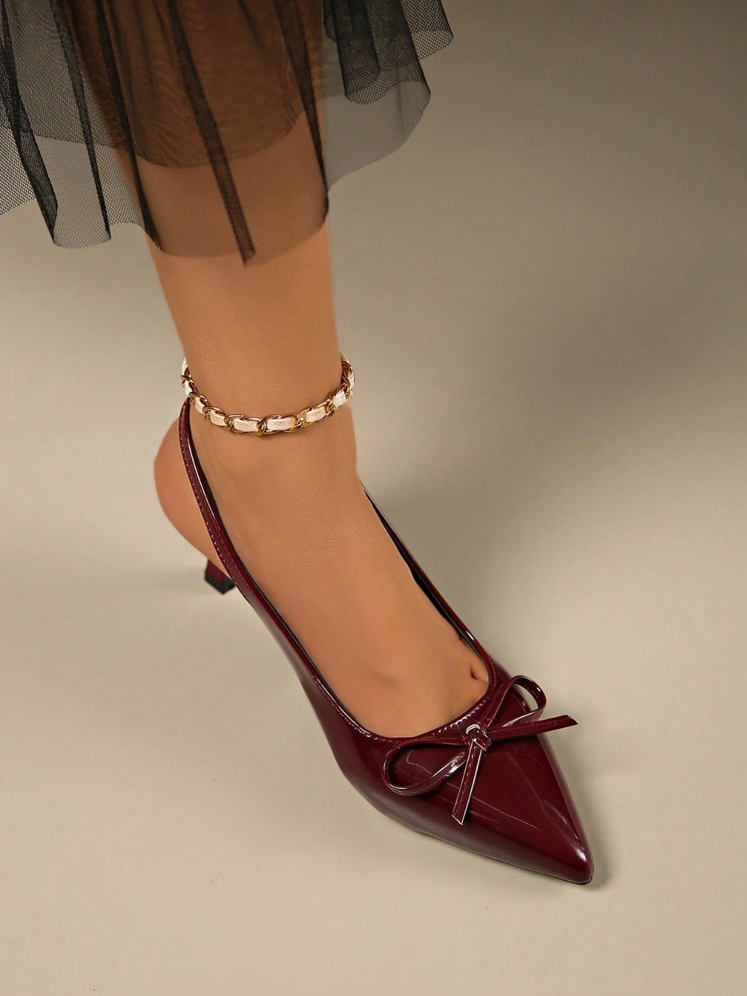 Cherry patent slingback heels with pointed toe, decorative bow detail, glossy finish, elegant stiletto silhouette.