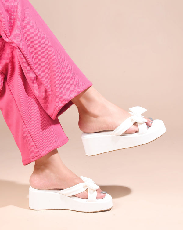 White platform wedge sandals featuring twisted bow straps and cushioned footbed for elegant comfortable everyday styling