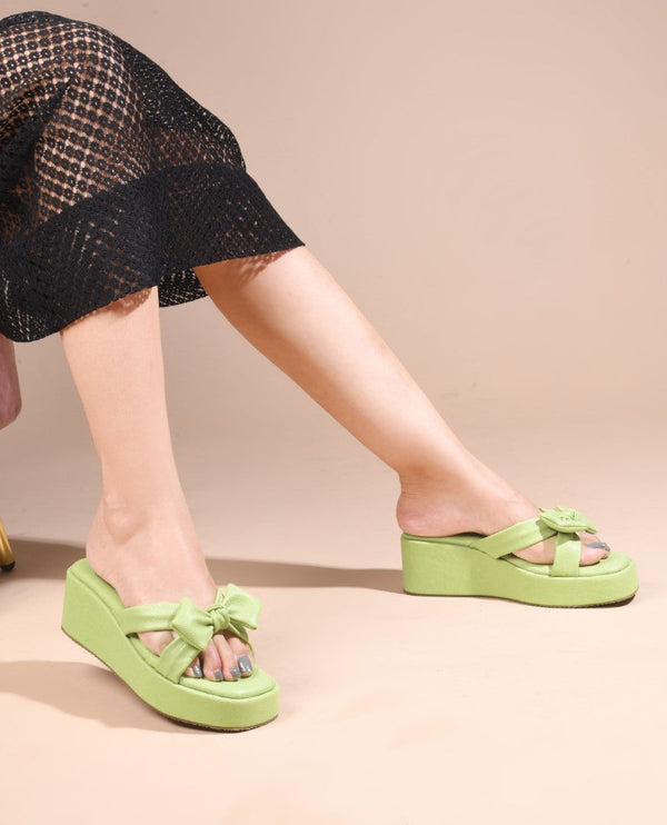 Green platform wedge sandals featuring twisted bow straps and cushioned footbed for elegant comfortable everyday styling