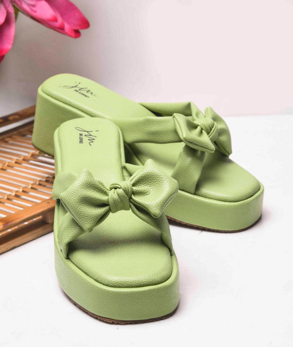 Green platform wedge sandals featuring twisted bow straps and cushioned footbed for elegant comfortable everyday styling