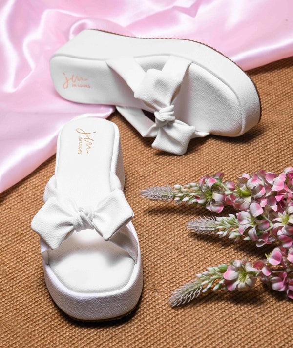 White platform wedge sandals featuring twisted bow straps and cushioned footbed for elegant comfortable everyday styling
