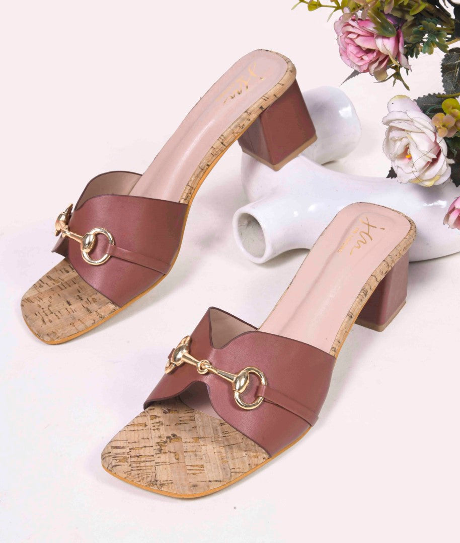 women's mules featuring a wide strap with a buckle embellishment and a cork-textured block heel
 Tan