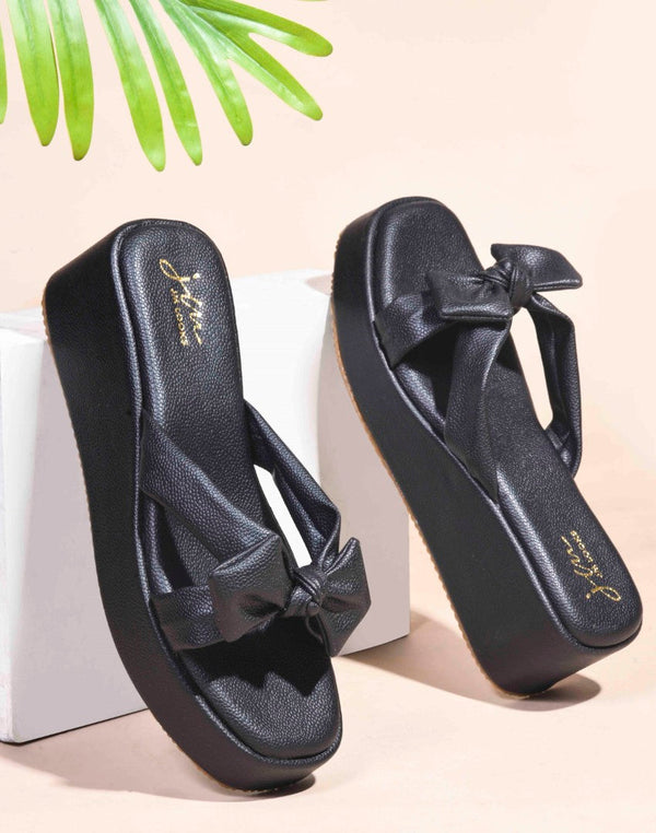 Black platform wedge sandals featuring twisted bow straps and cushioned footbed for elegant comfortable everyday styling