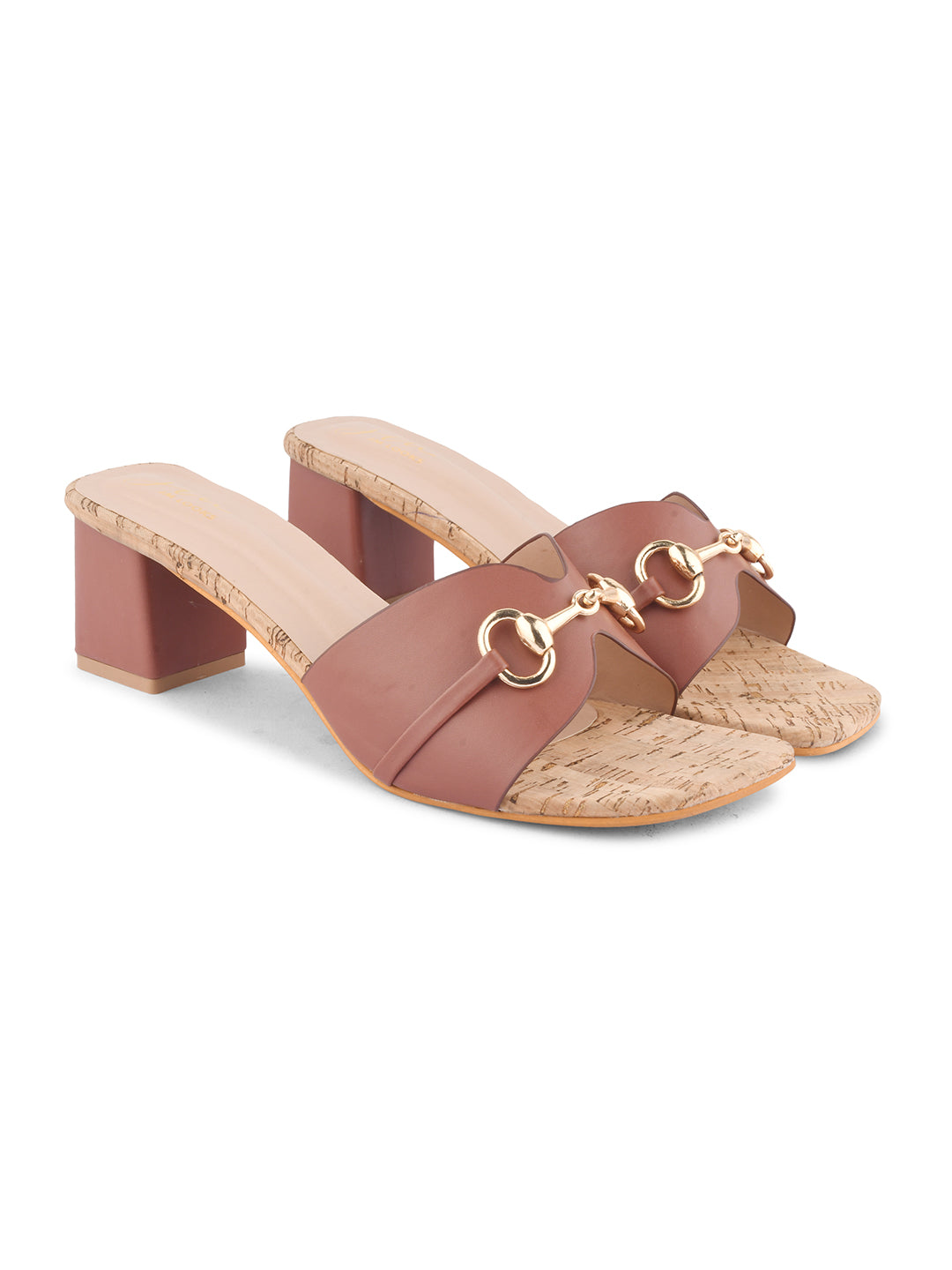 women's mules featuring a wide strap with a buckle embellishment and a cork-textured block heel
 Tan