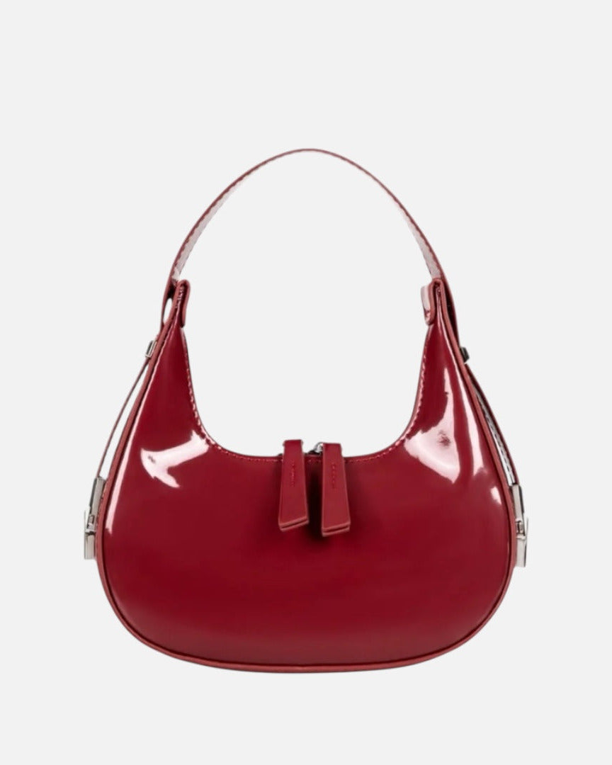 Burgundy half moon handbag for women in glossy patent finish with curved crescent shape and dual zip pulls.