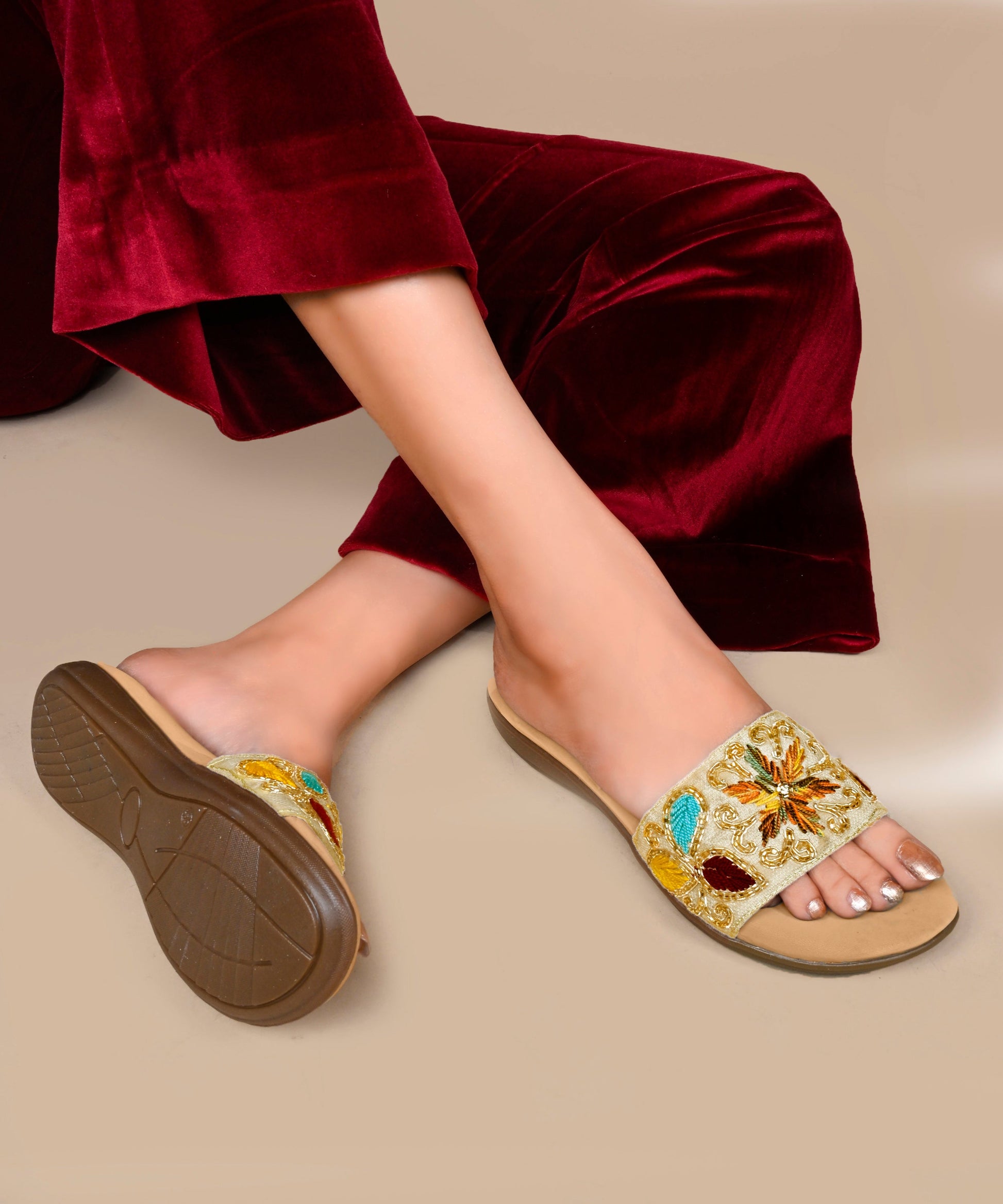 Embroidered slip-on slides for women in beige with multicolor floral thread work, gold beading, cushioned footbed.