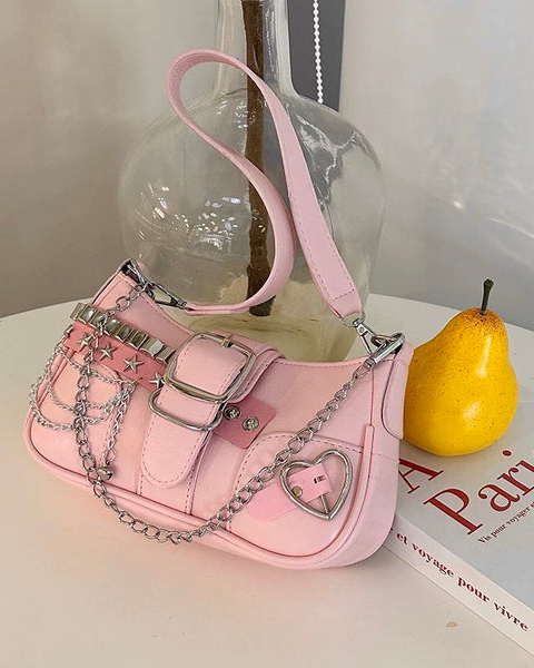 Baguette bag in pink featuring silver studs, star accents, buckle detail, layered chains, and heart charm