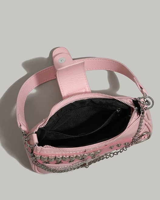 Baguette bag in pink featuring silver studs, star accents, buckle detail, layered chains, and heart charm