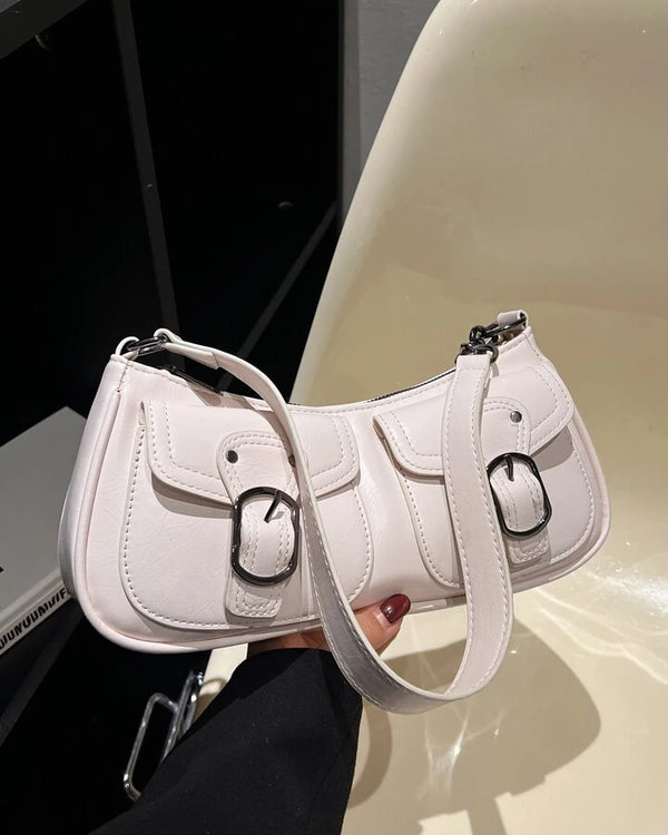 White shoulder bag with front buckle pockets, silver hardware, and adjustable strap for everyday wear.