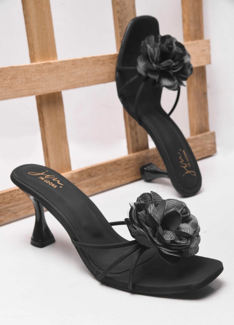women's heeled mules featuring a large floral embellishment on the strap
 Black