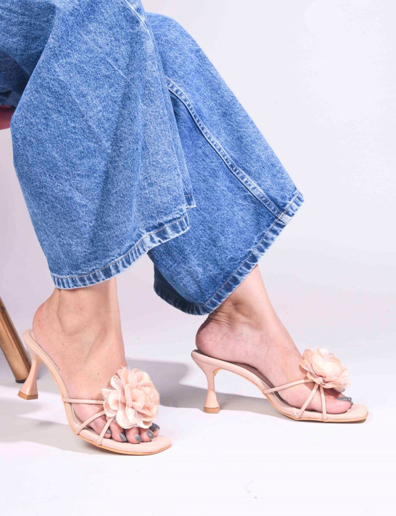 women's heeled mules featuring a large floral embellishment on the strap
 Purple