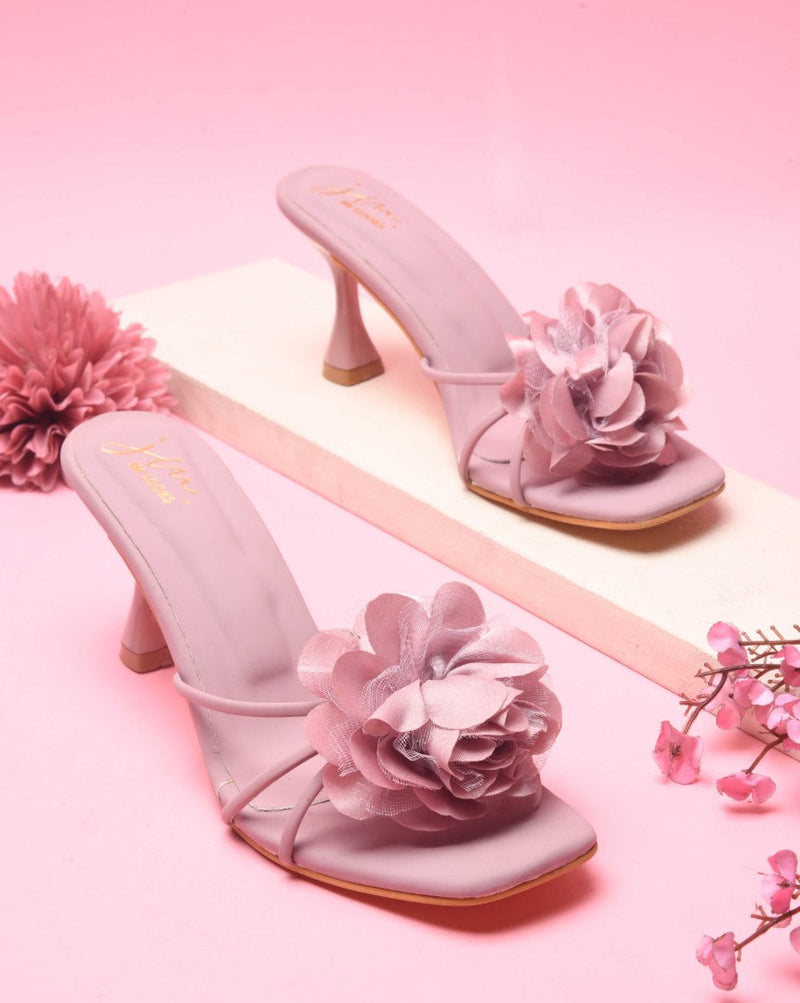 women's heeled mules featuring a large floral embellishment on the strap
 Nude