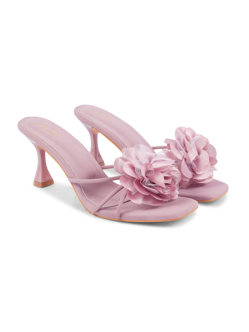 women's heeled mules featuring a large floral embellishment on the strap
 Nude