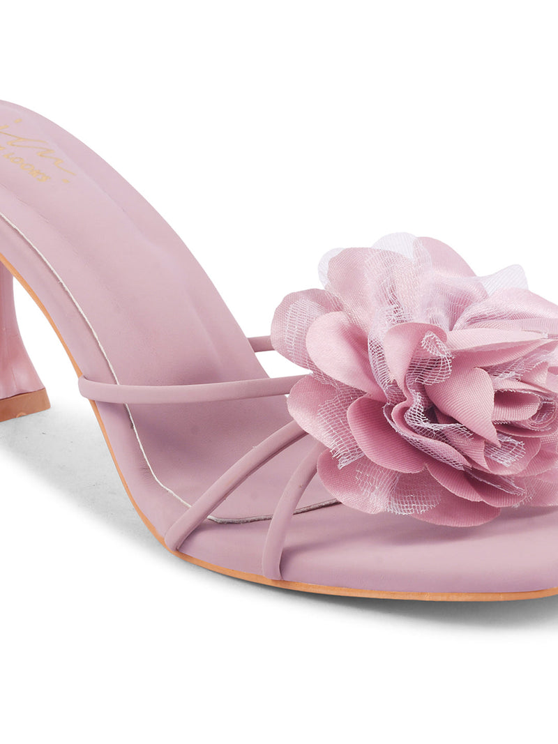 women's heeled mules featuring a large floral embellishment on the strap
 Nude