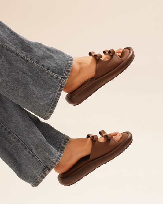JM Looks slide sandals featuring multiple bow details on the wide straps and a flat sole
 Brown