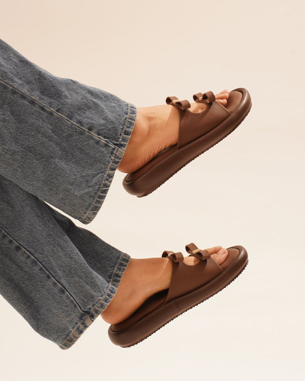 JM Looks slide sandals featuring multiple bow details on the wide straps and a flat sole
 Brown