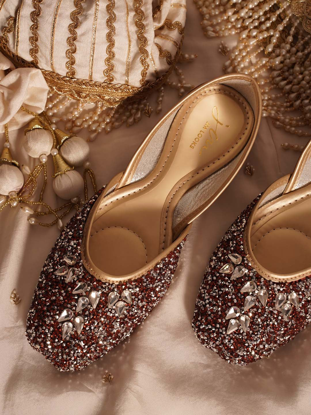 traditional juttis heavily embellished with sequins and large stone details in a floral pattern at the toe
 Copper
