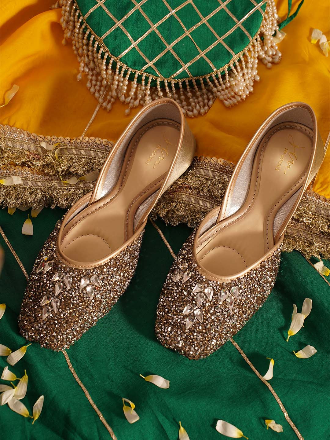 traditional juttis heavily embellished with sequins and large stone details in a floral pattern at the toe
 Green